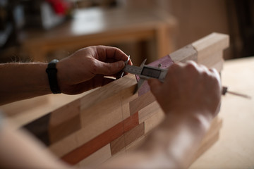 Hands of a carpenter measure the logs of wood with the help of Vernier caliper.