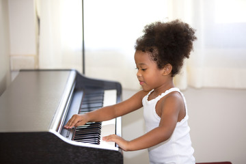 mix race girl kid sitting house playing piano