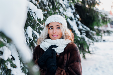 Young black woman wearing in fur coat and knitted hat walking in winter park