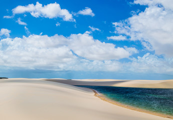 Fototapeta na wymiar A stream of water flowing through white dunes 