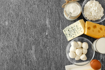 food and eating concept - close up of cottage cheese, bottle of milk, homemade yogurt with butter and chicken eggs on stone table