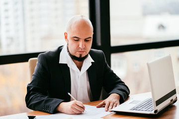 Businessman working on laptop and doing paperwork. Business planning and organization, paperwork concept