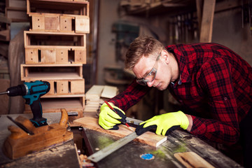 Young blonde man working with wood in his garage