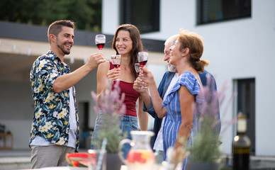 Portrait of people with wine outdoors on family garden barbecue.