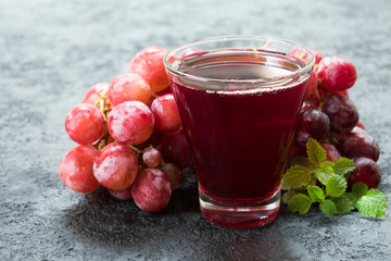 Glass of grape juice and a branch of grapes. Close-up.