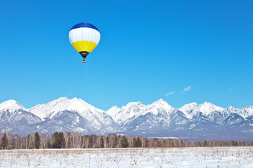 Fototapeta na wymiar Tourists take a balloon ride over the Tunka foothill valley and photograph the snow-capped mountains of the Eastern Sayan on a sunny winter day. Christmas holidays, winter travel