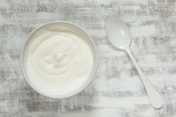 Fototapeta na wymiar Sour cream in white bowl with white spoon on white background