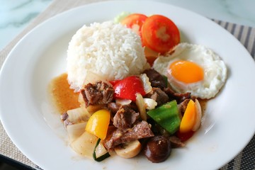 Fried beef with oyster sauce and fried egg on white plate. Thai style food concept.