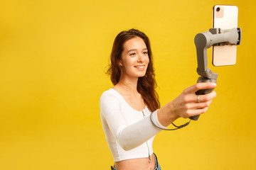 Young blogger girl with three-axis electronic stabilizer gimbal. Makes a selfie and video blog.
