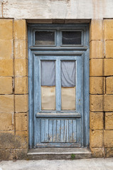 Door with blue peeling paint in the bastide town of Castillones, Southwest France.