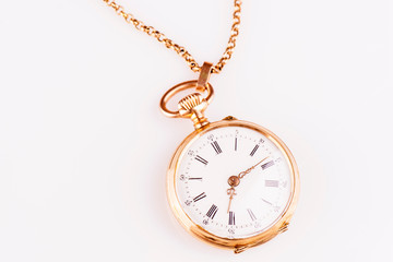 An antique red gold pocket watch against a white background