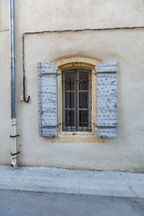 Window of a house on a street in the historic town of Arles, south of France. with blue painted traditional wooden shutters.