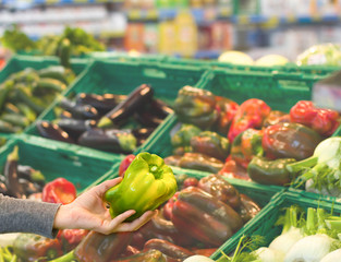 Female hand choosing pepper at supermarket. Concept of healthy food, bio, vegetarian, diet.