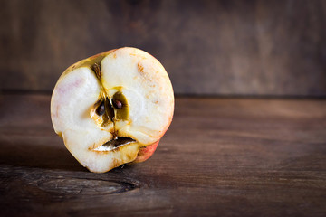 Ugly apple in a cut on a wooden background.