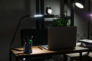 Comfortable workplace with laptop in evening