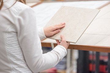 Woman choosing a new ceramic floor tile in a construction store.