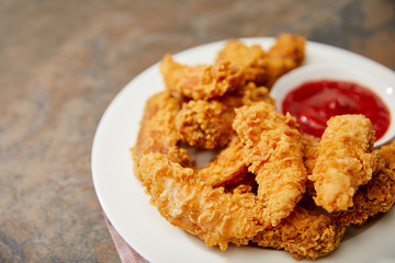 close up view of delicious chicken nuggets with ketchup on stone surface