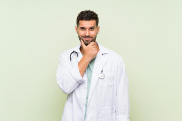 Young doctor man over isolated green wall laughing