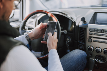 Naklejka premium Caucasian man sitting in car and typing message