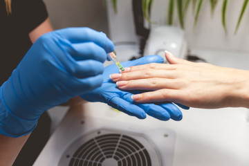 Manicurist applying nourishes nail and cuticle oil