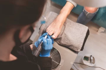 Fotobehang Pedicure Pedicure master uses nail file drill  for preparing nails for pedicure