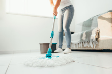 Cropped image of young woman in using a mop while cleaning floor in the house - Powered by Adobe