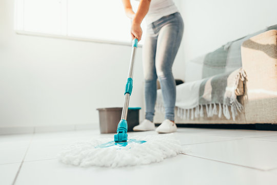 Cropped image of young woman in using a mop while cleaning floor in the house
