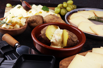 raclette cheese melting on potato served in individual skillets. swiss raclette