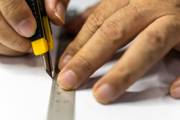 Close up hands with the tool cutting a paper