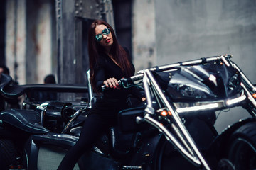 Plakat young woman in sunglasses posing sitting on a custom motorcycle