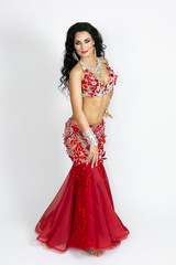 Fototapeta premium Brunette in a beautiful long dress to perform belly dance on a white background