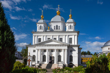Fototapeta na wymiar Russia, Golden Ring, Yaroslavl, near Volga river: Front view of famous orthodox onion domed Kasan Convent in the city center of the Russian town with green garden, women and blue sky.