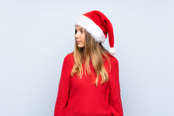 Girl with christmas hat over isolated blue background looking side