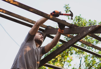 Man building wooden roof working with hammer