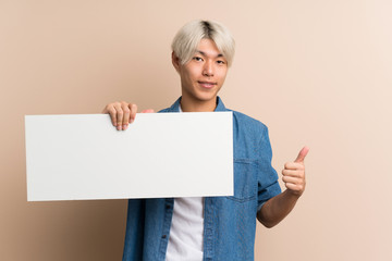 Young asian man over isolated background holding an empty white placard for insert a concept