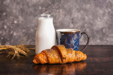 Tasty sweet croissant with coffee and milk on table