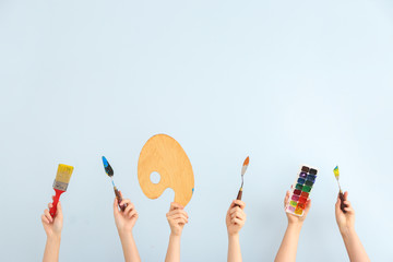 Female hands with painter's supplies on light background