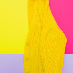 Flat lay fashion set: yellow knitted cardigan on pastel bold background. Minimalist