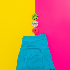 Turquoise jeans with donuts on bright pink and yellow background. minimalist