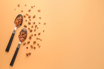 Spoons with tasty granola on color background