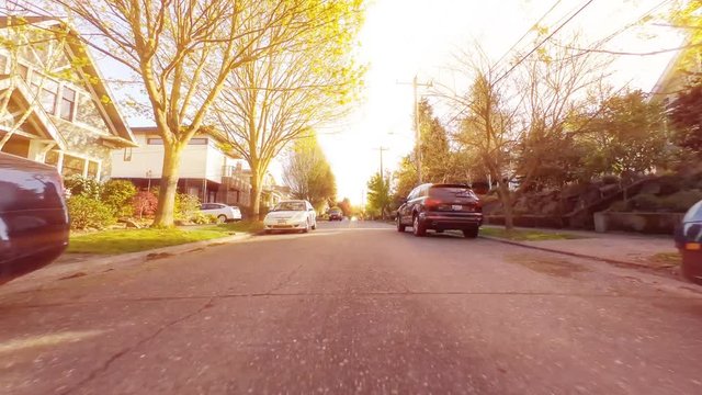 Time lapse footage of a car driving around a city neighborhood on a sunny afternoon, as viewed from the front of the vehicle at street level