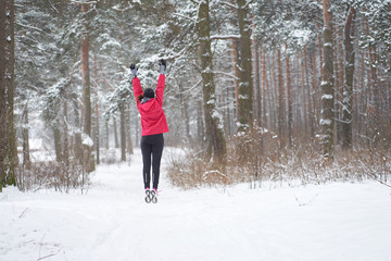 Fototapeta na wymiar Winter run. Workout. Young sporty woman jumping in winter forest.