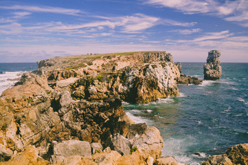 Fototapeta na wymiar The rocky peninsula in the ocean with a small cliff on the side. Portugal. Europe