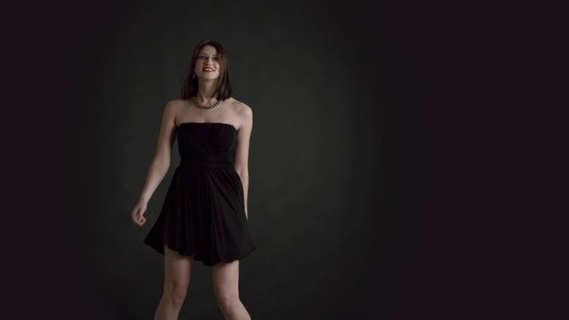 Studio portrait of 30s woman on black background evening makeup celebration look dancing and her dress blowing and flying in slow motion