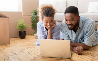 Black Spouses Using Laptop Lying On Floor Indoor