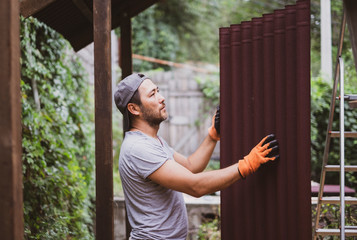 Man building roof and holding roof material.