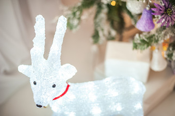 Christmas luminous deer under the tree close-up. Room decor with a deer under Christmas and copy space.