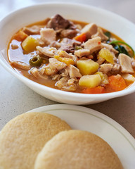 Mondongo soup, made with cow stomach, traditional dish of the Caribbean countries and Venezuela, served in a deep white bowl, accompanied with arepas and avocados