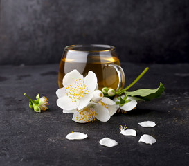 Cup of green tea and Jasmine flowers on a black background. Herbal medicine.