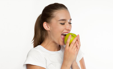 Young Lady Biting Apple Standing Over White Background, Studio Shot